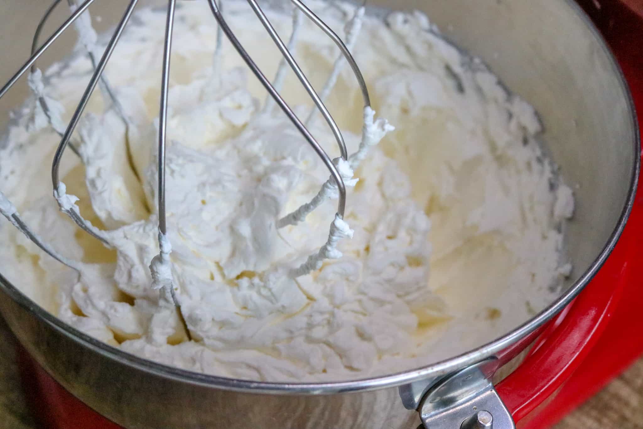 Cream being whipped with the whisk attachment in a mixer.