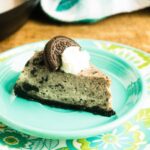 A slice of Instant Pot Oreo Cheesecake served on a blue plate and topped with whipped cream