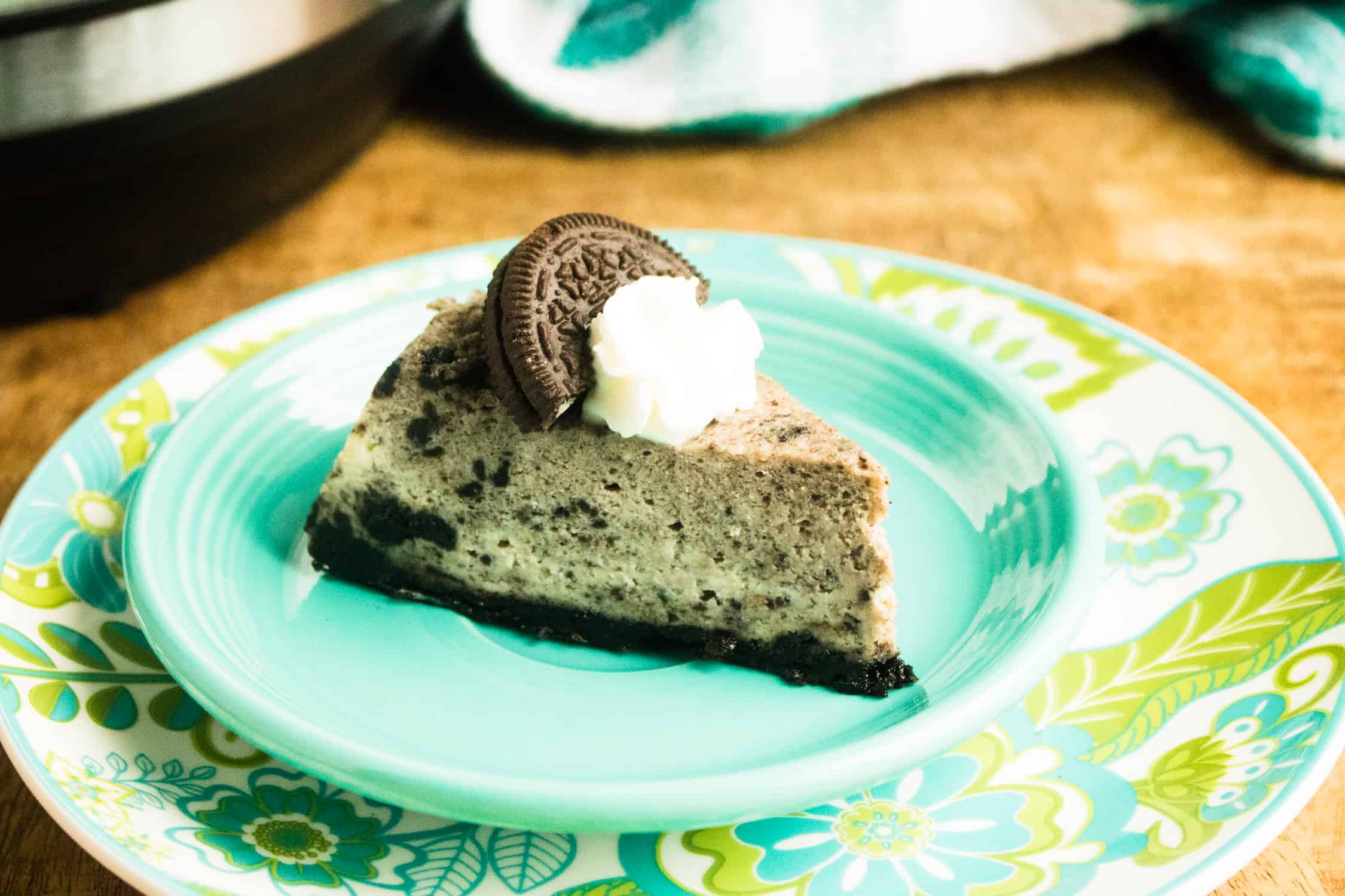 A slice of Instant Pot Oreo Cheesecake served on a blue plate and topped with whipped cream
