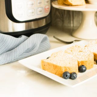 Slices of Instant Pot Pound Cake on a white serving tray and garnished with blueberries and powdered sugar
