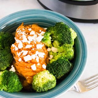 One cooked Instant Pot Sweet Potato served with steamed broccoli and garnished with cheese