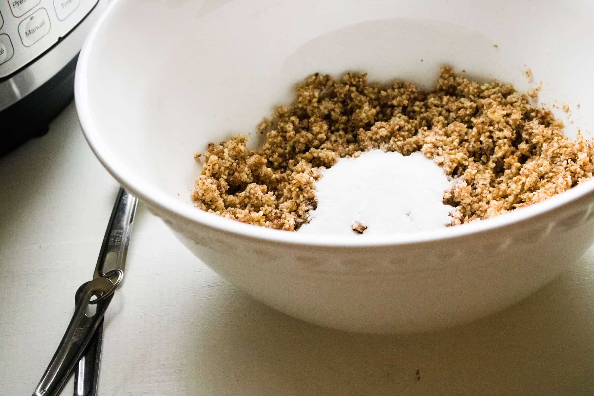 The ingredients for Instant Pot Grain-free Keto Cheesecake crust in a white mixing bowl