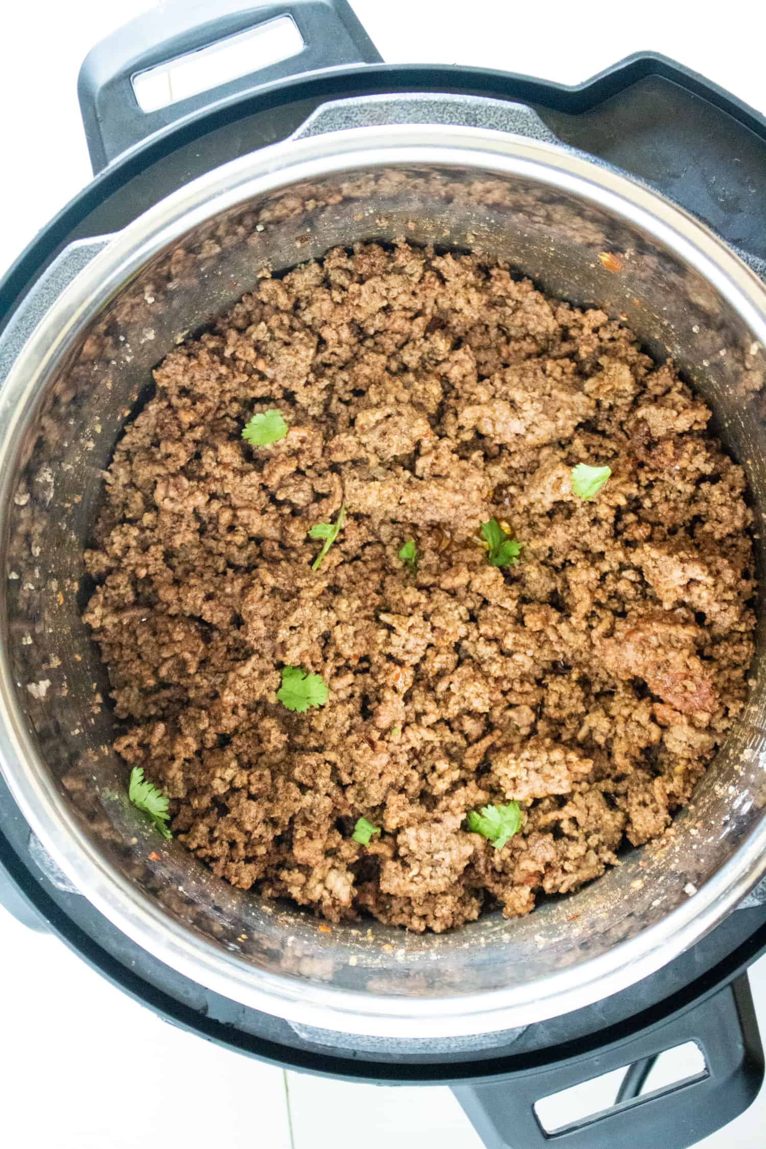 Cooked Instant Pot Taco Meat with sprigs of cilantro in it