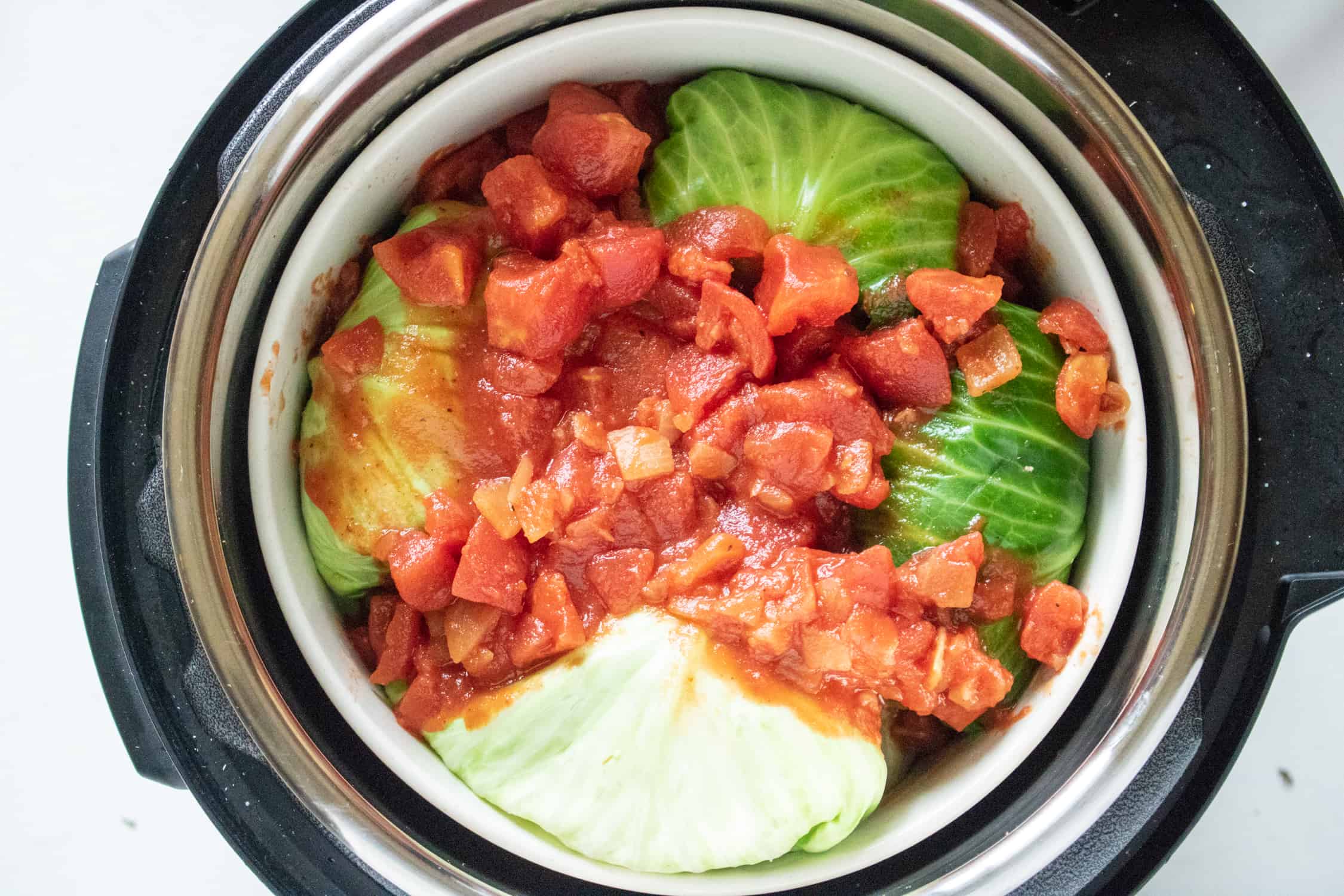stuffed cabbage rolls in an Instant Pot topped with diced tomatoes