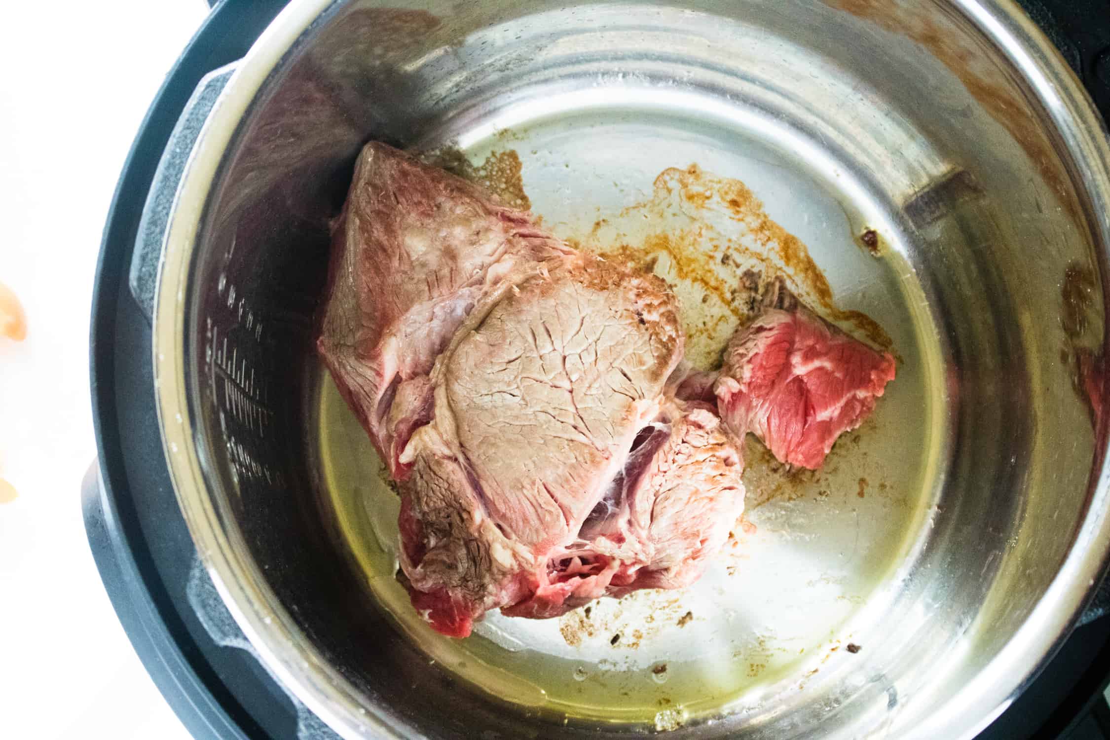 A beef roast being seared in an Instant Pot 