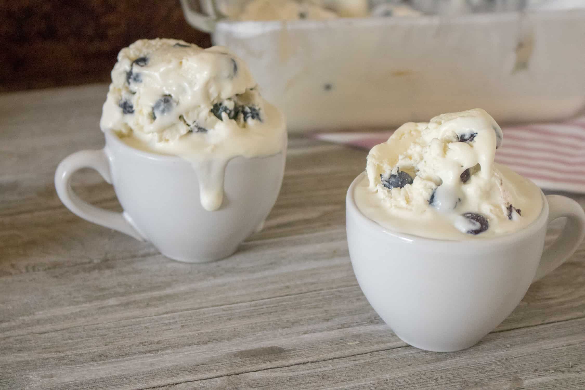 two white ceramic cups with large scoops of blueberry lemon no churn homemade ice cream in them