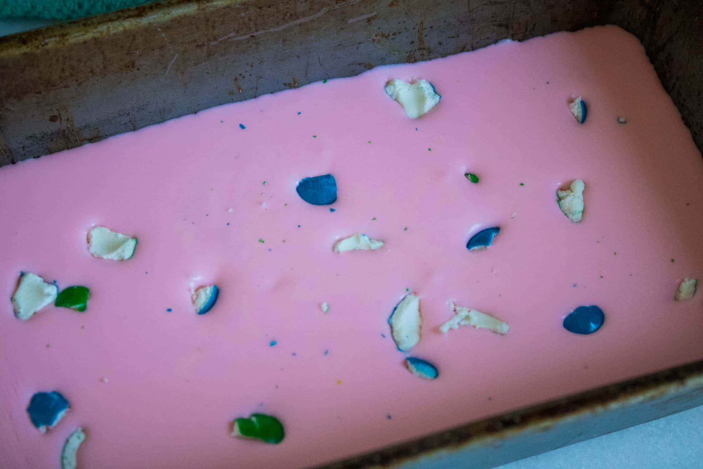 oblong pan with pink no-churn ice cream in it with gumball pieces scattered on top in white blue and green