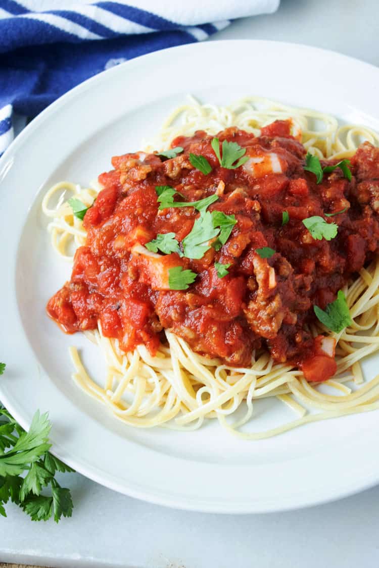 meat sauce served on noodles on a white plate
