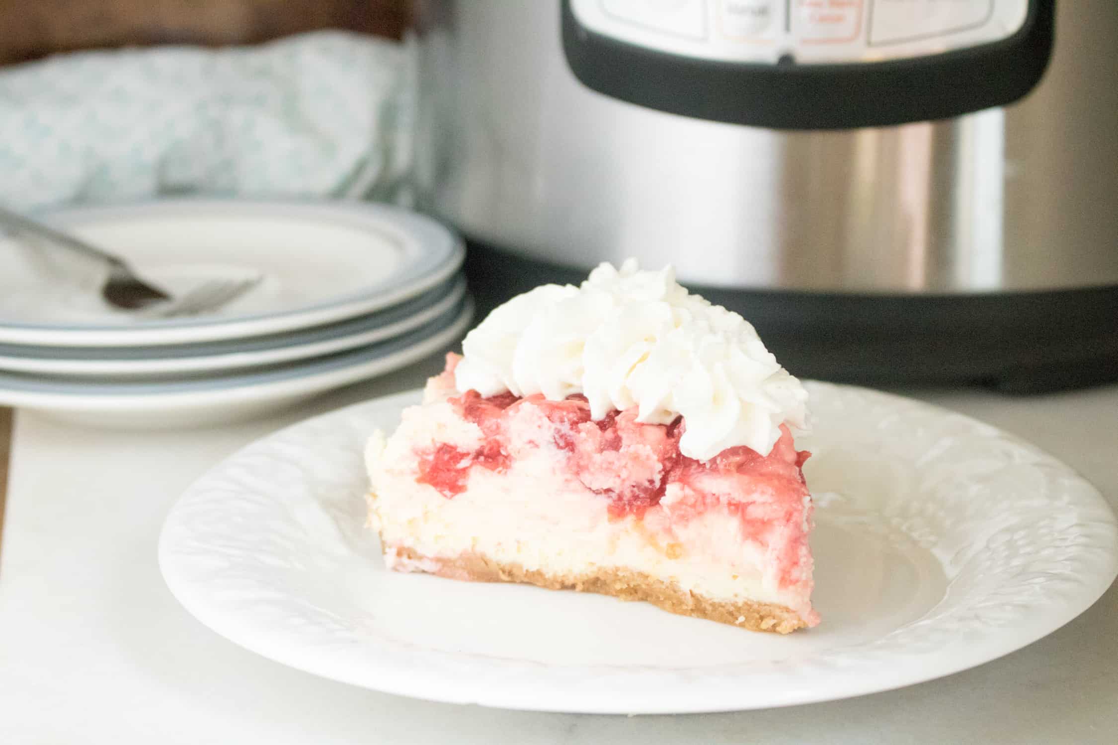 One slice of Instant Pot Cherry Swirl Cheesecake served on a white dessert plate