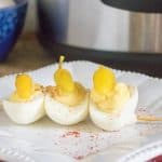 Permalink to: Instant Pot Deviled Eggs Recipe Finished Instant Pot Deviled Eggs Recipe with three eggs threaded on a skewer and served on a white plate