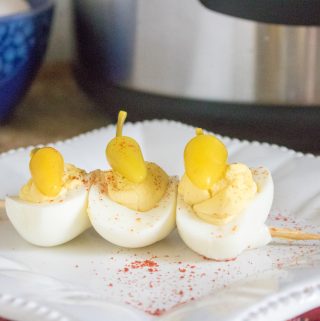 Finished Instant Pot Deviled Eggs Recipe with three eggs threaded on a skewer and served on a white plate