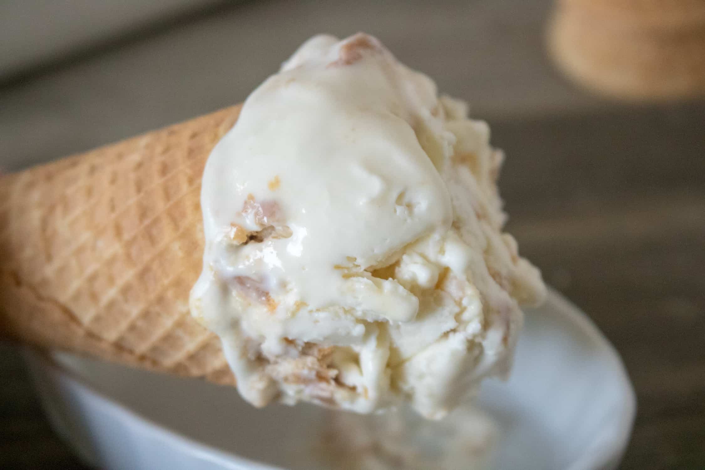 no-churn peanut butter ice cream on a sugar cone being held over a white bowl