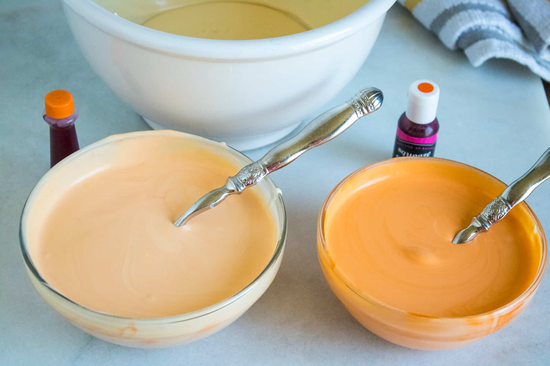 orange food coloring being added to two smaller bowls filled with no-churn ice cream base 