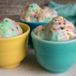 Birthday Cake No-Churn ice cream served in three different colored mugs and topped with rainbow sprinkles