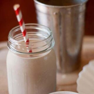 chocolate peanut butter milkshake in jar with red and white striped straw