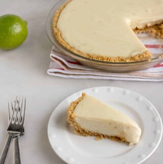 One slice of Quick and Easy Key Lime Pie cut from the pie and served on a white dessert plate with a silver fork