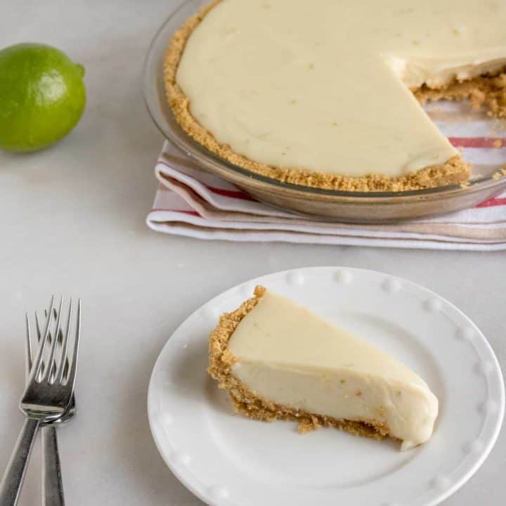 One slice of Quick and Easy Key Lime Pie cut from the pie and served on a white dessert plate with a silver fork