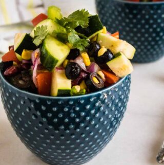 one serving of picnic salad in a blue polka dot bowl set next to a silver fork