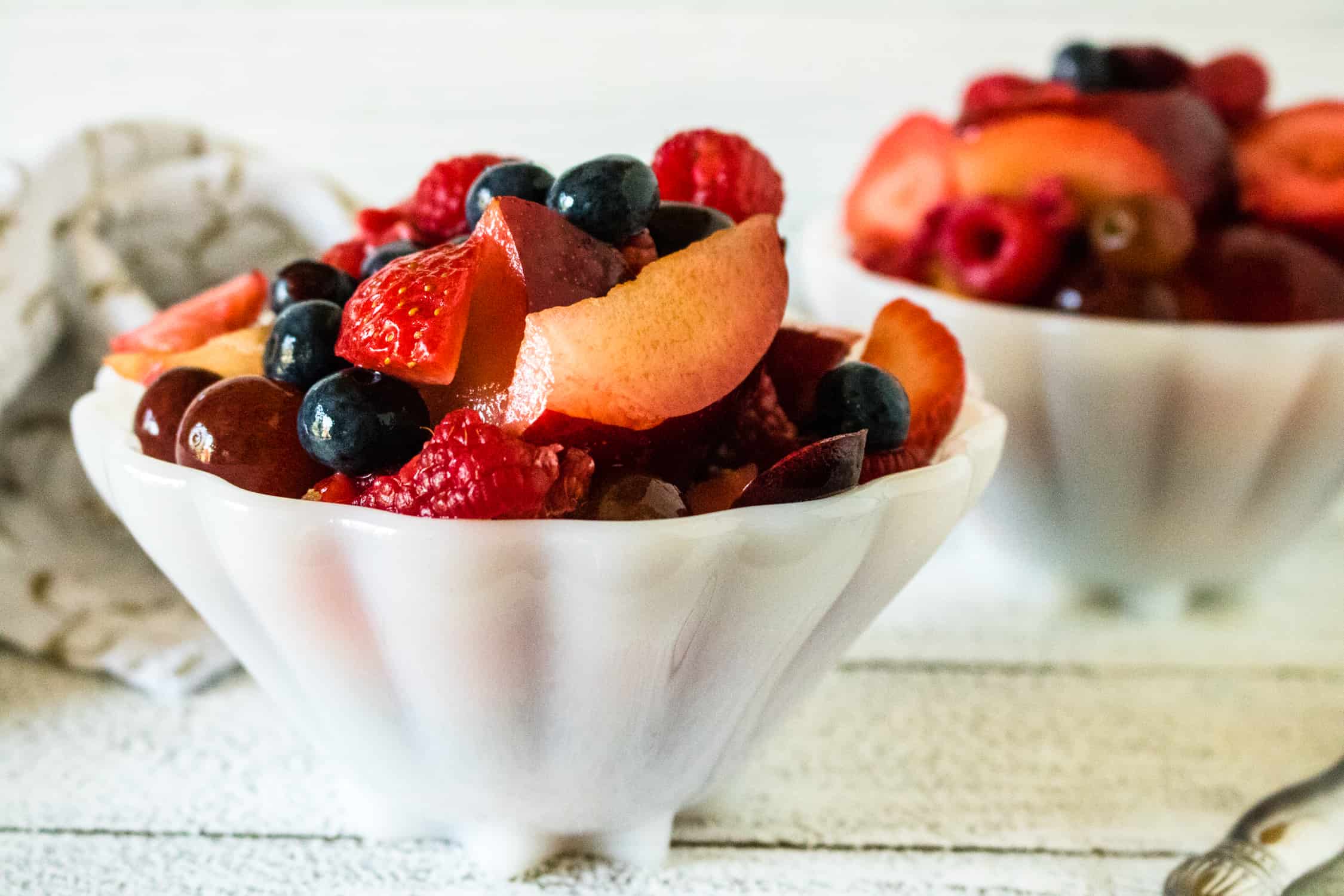servings of fresh fruit salad with Honey Lime Dressing served in white scalloped bowls