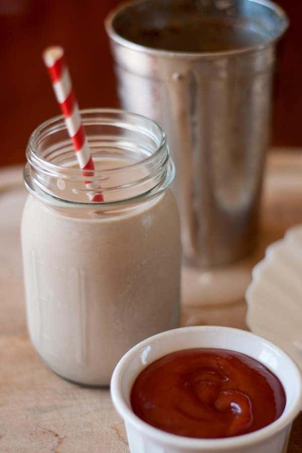 chocolate peanut butter milkshake in jar with red and white striped straw