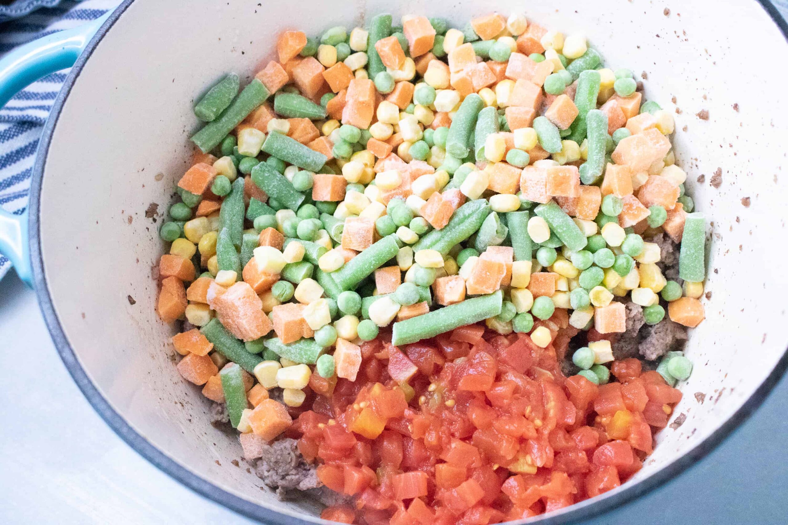 mixed vegetables and tomatoes in stockpot making Poor Man's Soup