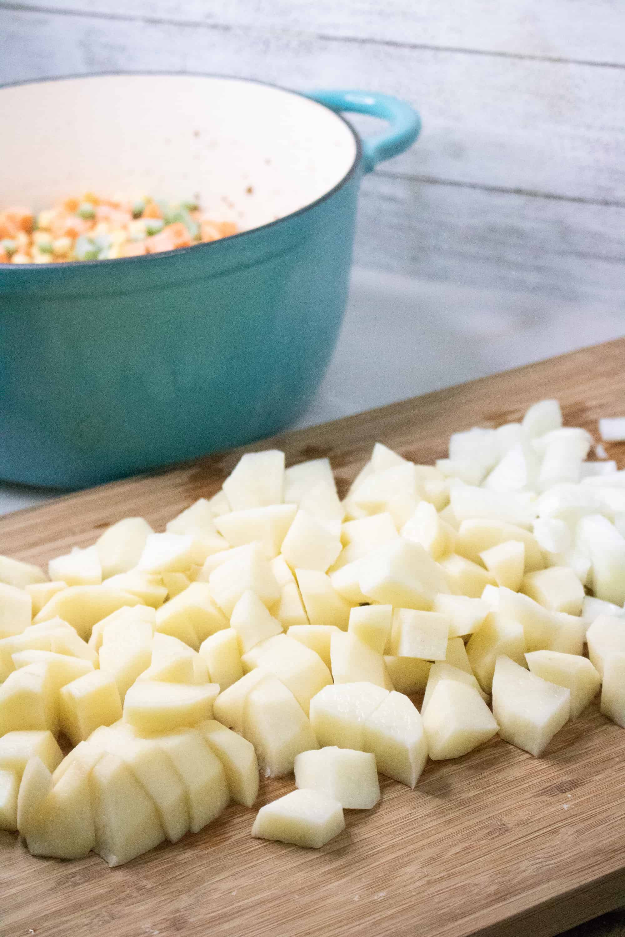 chopped potatoes with blue stock pot in the background for Poor Man's Soup