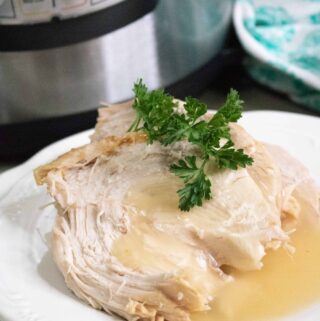 One serving of Instant Pot Turkey on a white plate and set in front of the Instant Pot