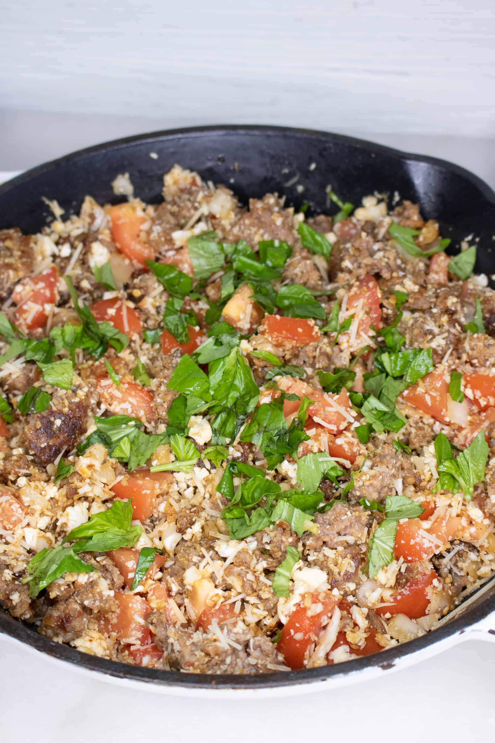 Italian sausage, cauliflower rice, tomatoes, onions and lettuce cooked together in an iron skillet