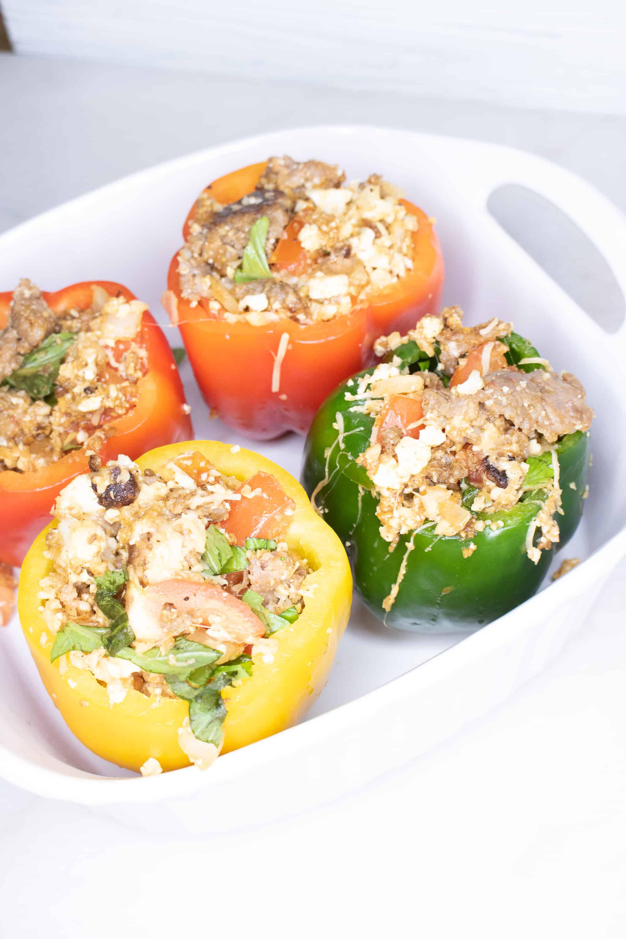 Italian sausage and cauliflower rice stuffed peppers in a white serving dish