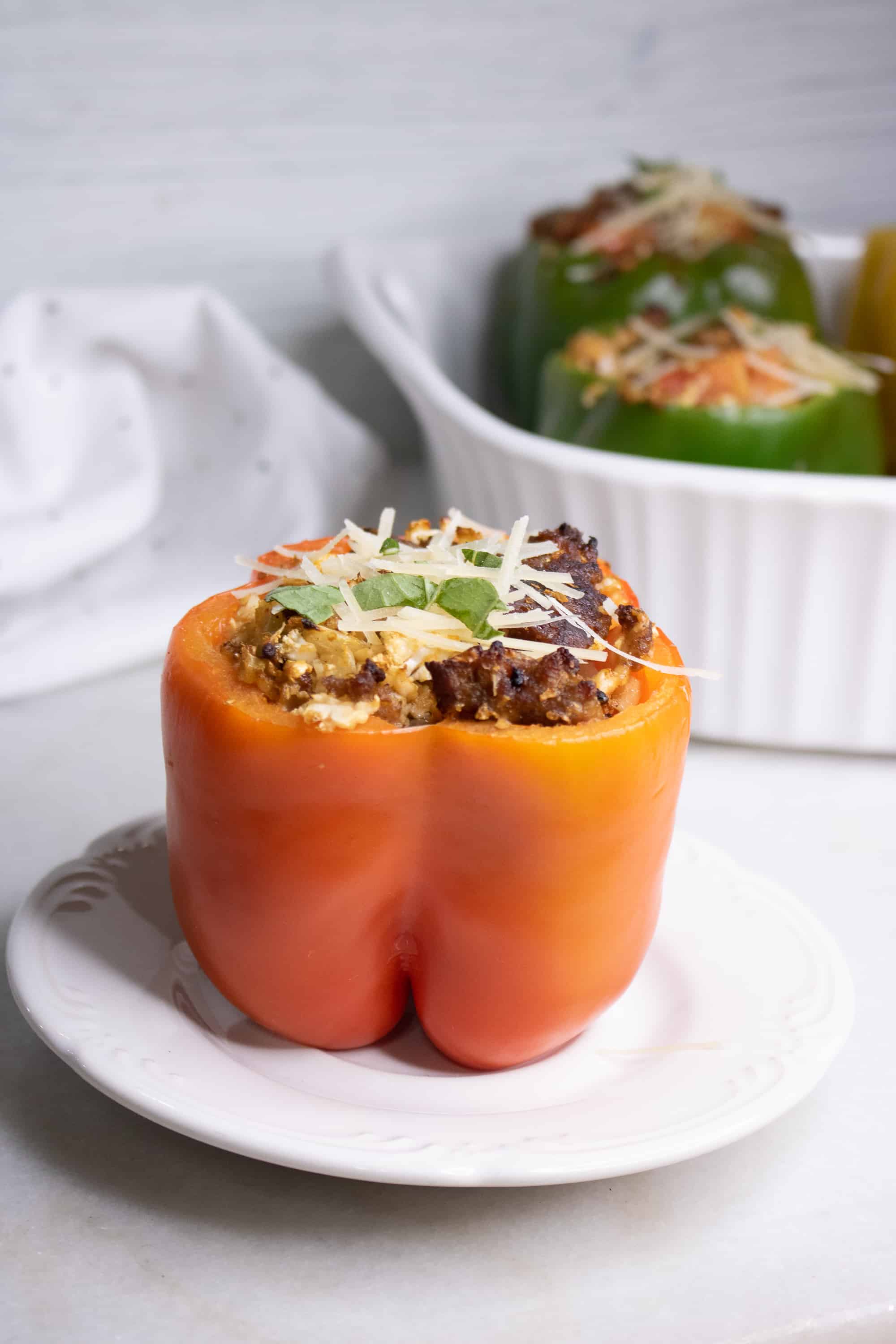 An Italian sausage and cauliflower rice stuffed pepper sitting on a white serving plate