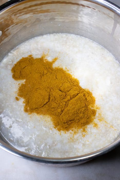 Curry powder added on top of the chicken, cauliflower rice and liquid in the soup pot