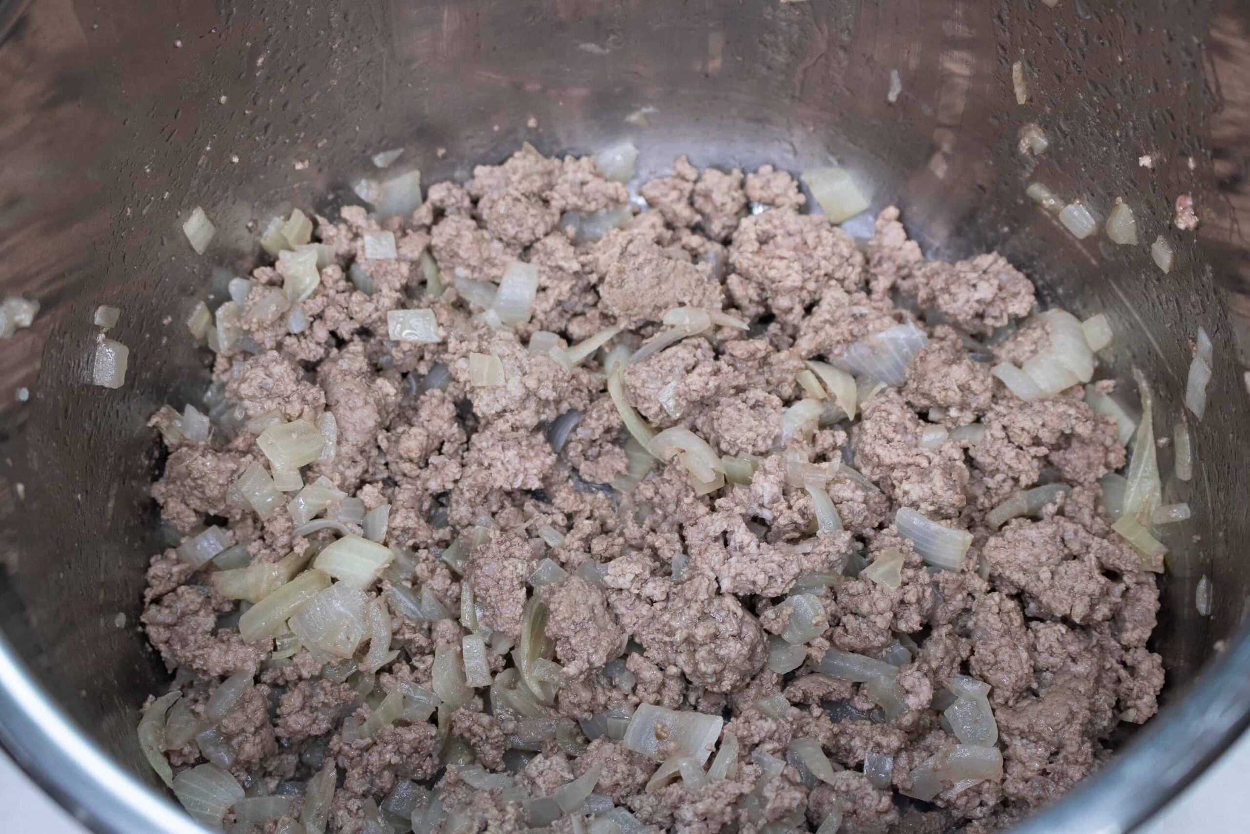 cooked beef and onions for this Instant Pot Soup receip being put back inside the instant pot f