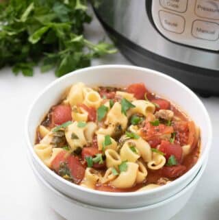 Instant Pot Poor Man's Beefy Tomato Macaroni Soup served in a white bowl set in front of the instant pot