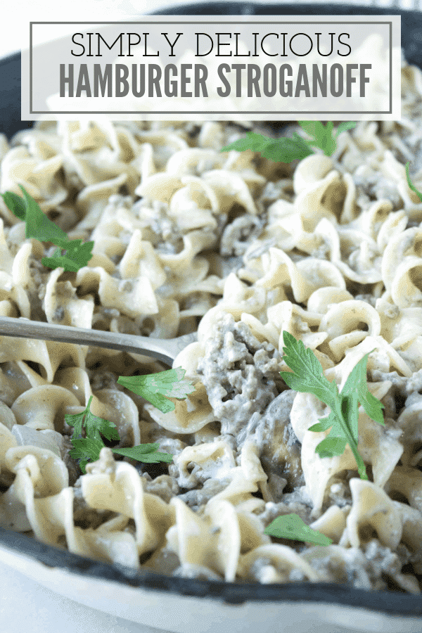 cast iron pan full of hamburger and pasta casserole with pieces of parsley on top. At the top of the photo are the words, 'Simply delicious hamburger stroganoff'