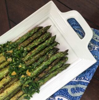 grilled marinated asparagus with gremolata served on a white ceramic dish