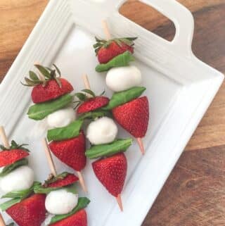 strawberry caprese skewers on a white platter