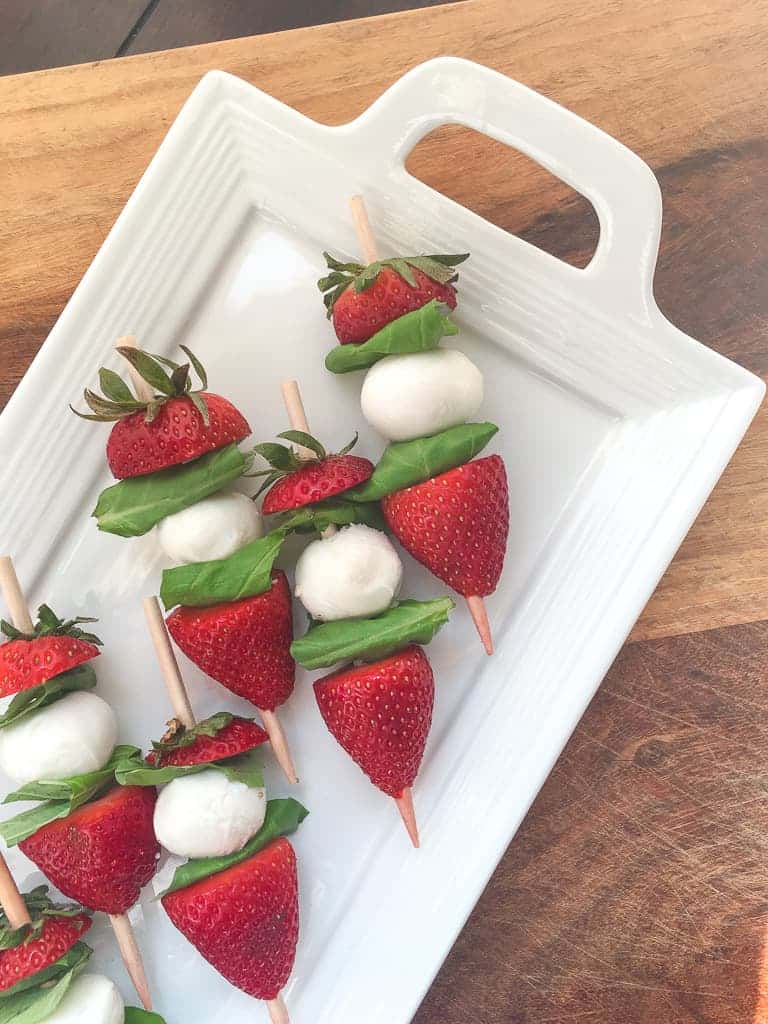 strawberry caprese skewers on a white platter