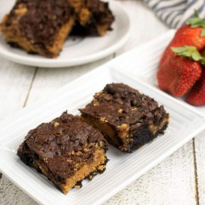 peanut butter brownies on white plate with strawberries in the background