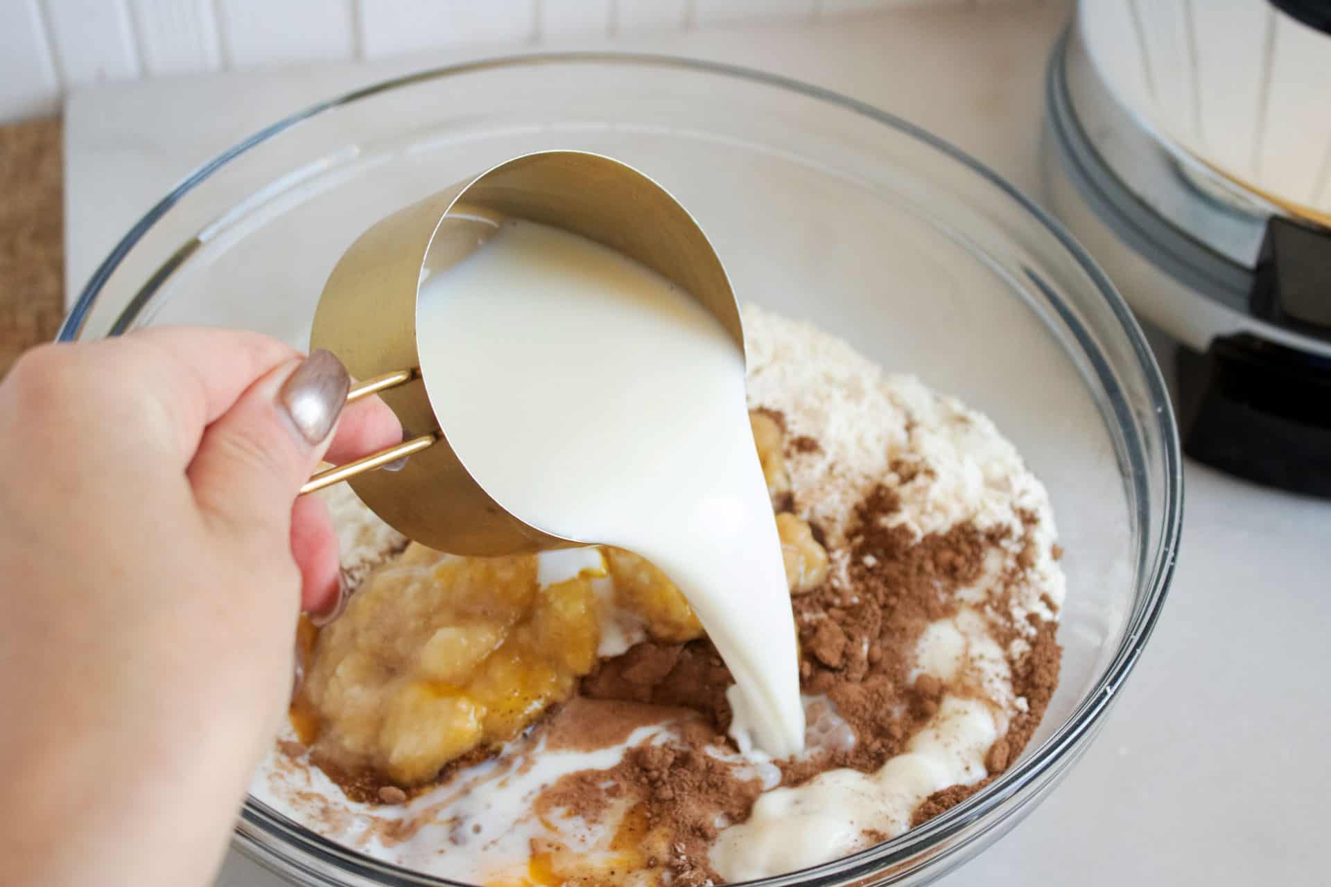 pouring milk into a bowl with waffle batter