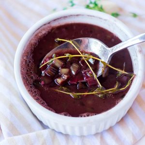 white ramekin with red wine steak sauce and a spoon resting in the bowl