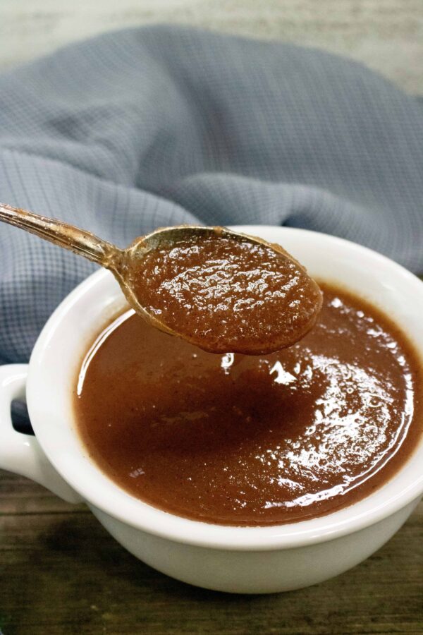 spoon of apple butter above white bowl 