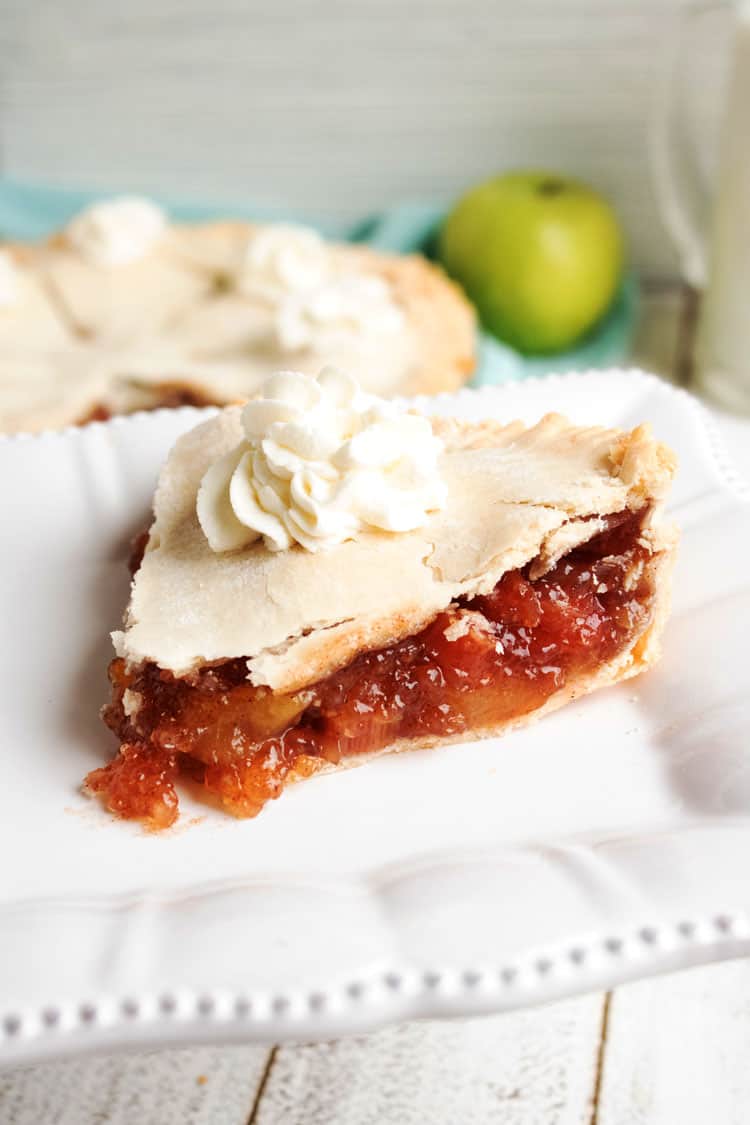 slice of rhubarb apple pie on a white plate with whipped cream on top 
