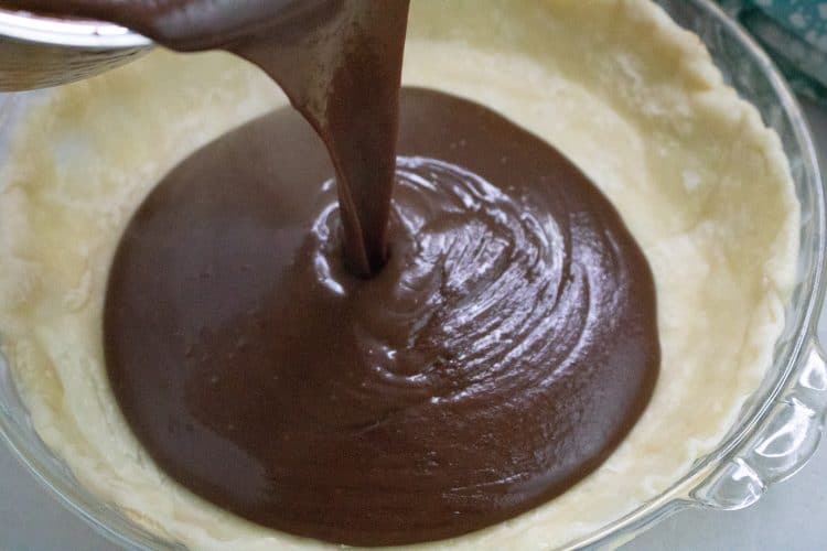 chocolate pie filling being poured into pie shell