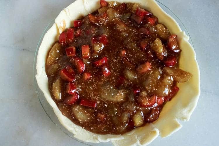 filling in pie pan with crust for apple rhubarb pie 