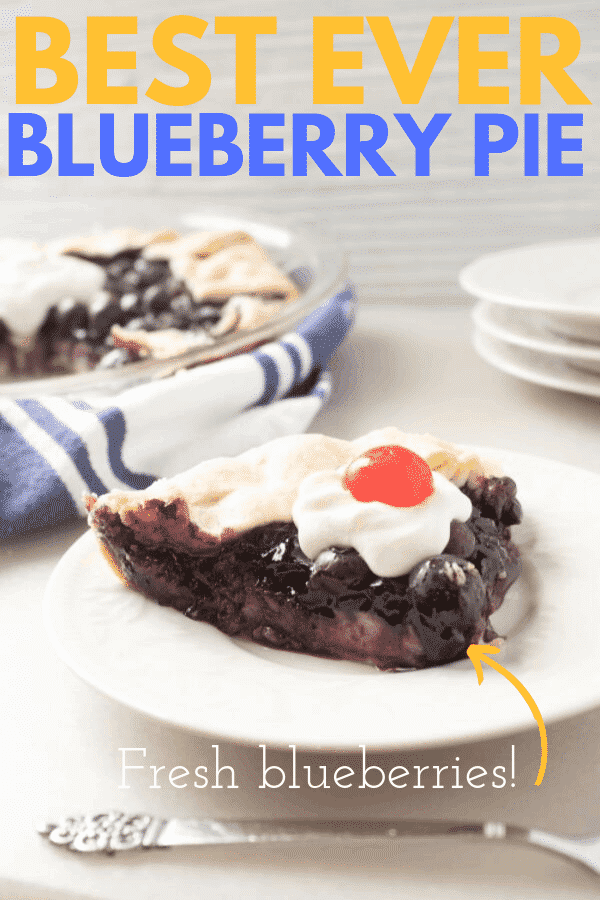 blueberry pie slice on a white plate with a pie and blue and white towel in the background