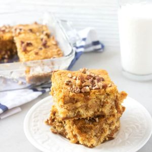 pumpkin dump cake on a white plate with a glass of milk and cake in pan in the background