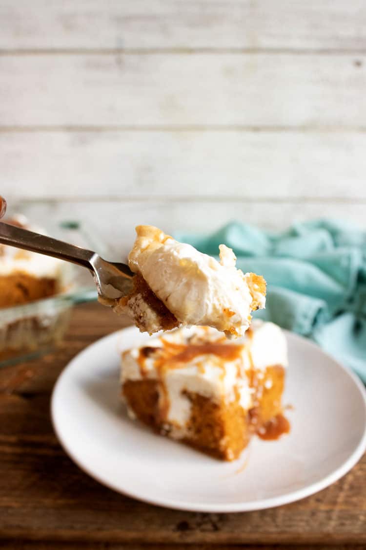 pumpkin poke cake on white plate with blue towel in the background