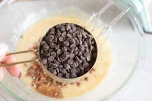 measuring cup with chocolate chips adding to mixing bowl