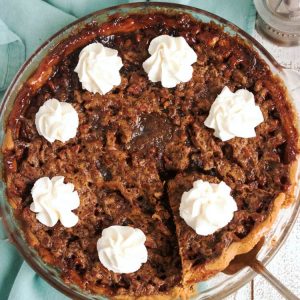 full derby pie with overhead shot. whipped cream dollops on top.