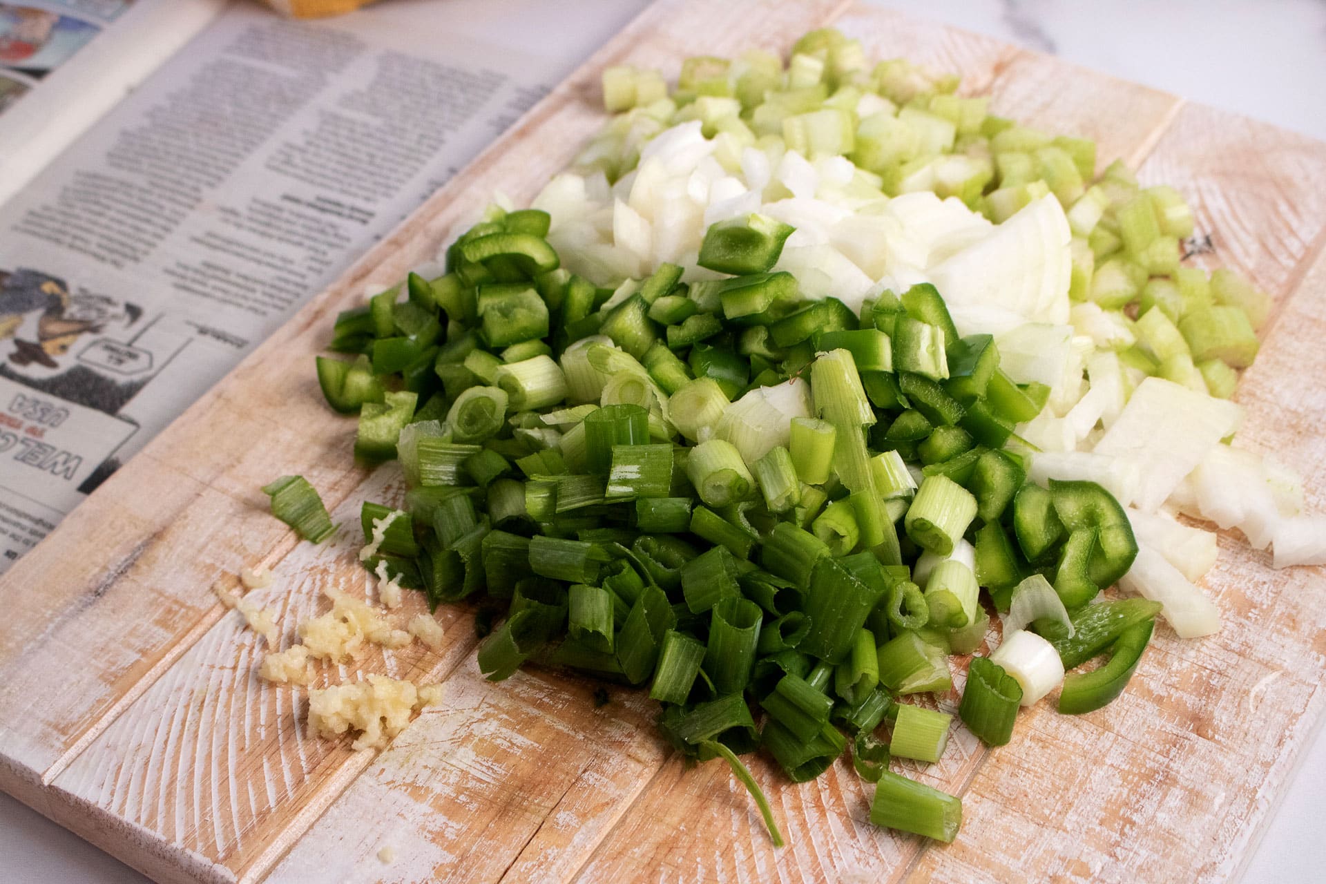 Chopped celery, green bell pepper, onion, scallions and garlic on a cutting board